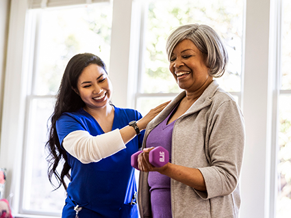 At home nurse helping senior woman with physical therapy at home